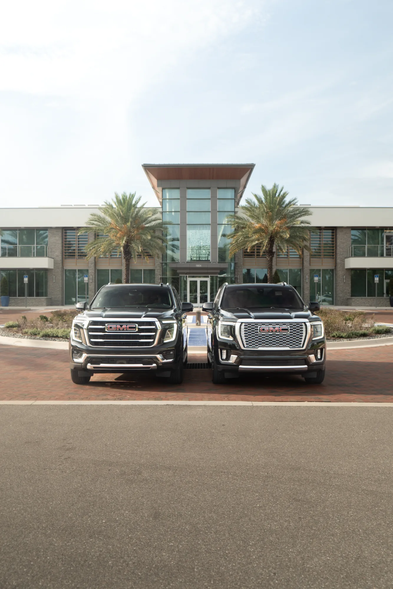 Two black GMC SUVs parked front-to-front outside an executive office