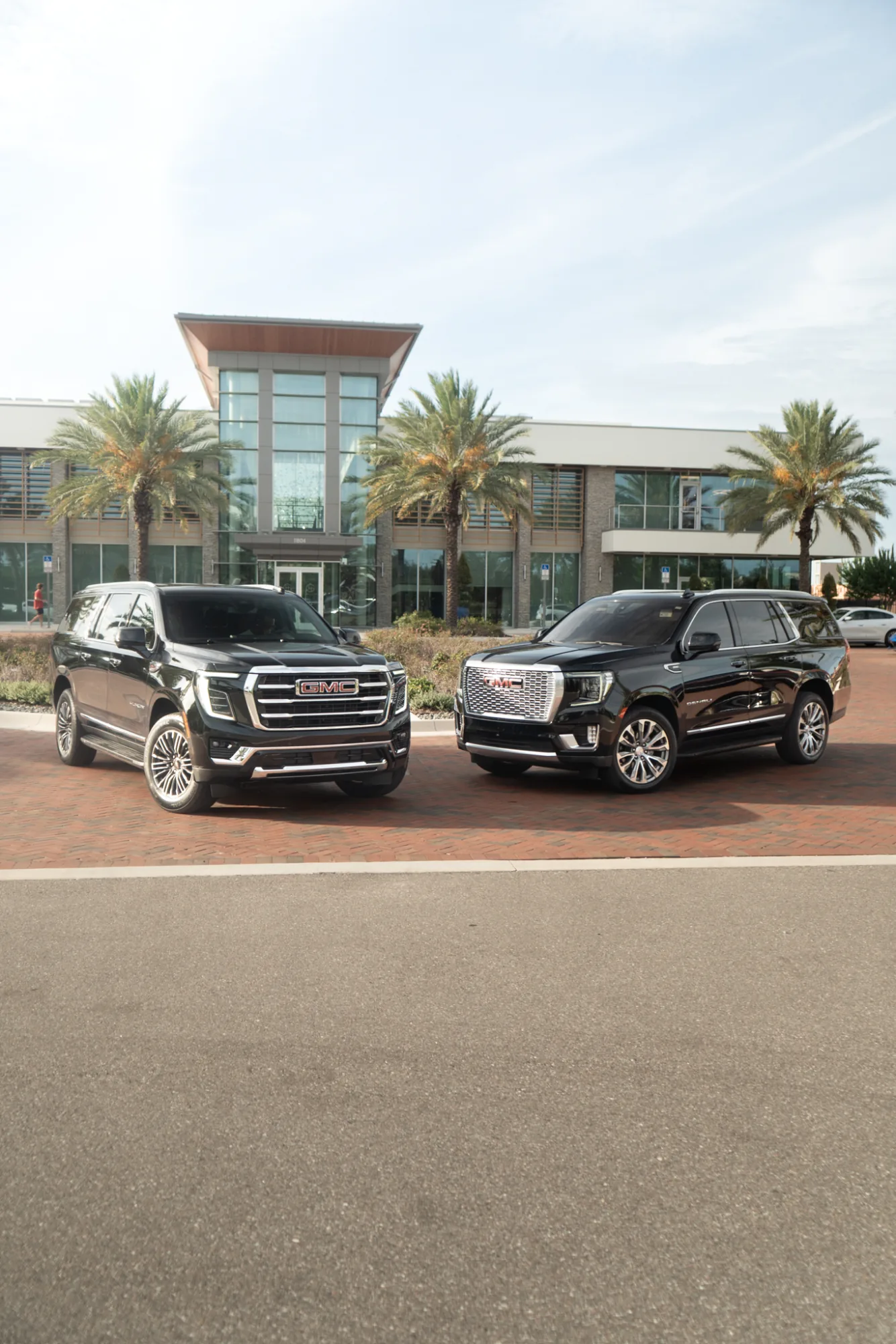 Two GMC Denali SUVs detailed and staged outside a modern building