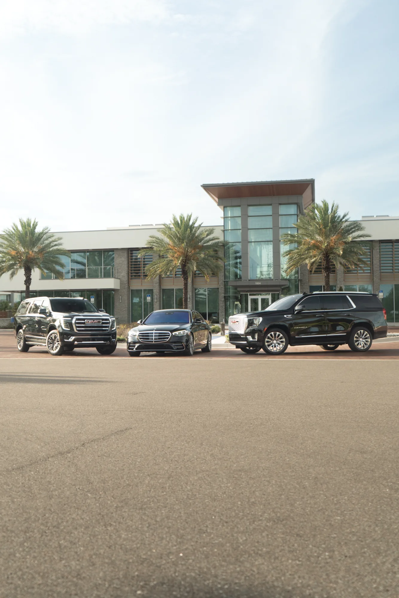 The chauffeur fleet — two SUVs flanking a Mercedes S-Class